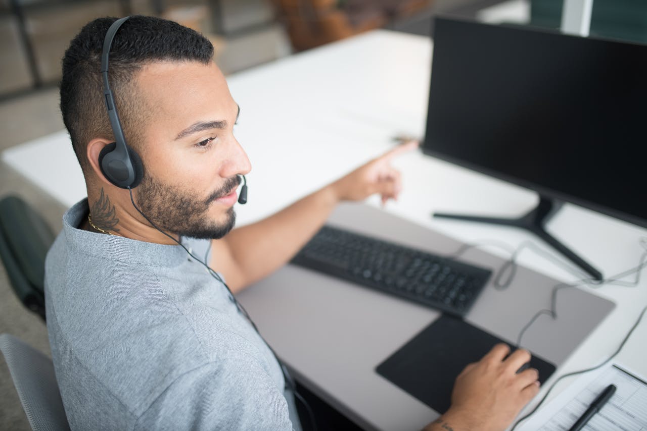 The Art of Drawing Readers In: Your attractive post title goes here Customer service agent using a computer and headset within a modern office setting.